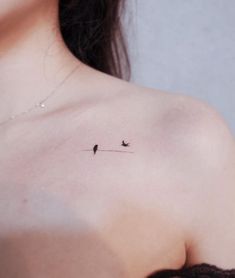 a woman's chest with two birds on the line behind her left shoulder tattoo