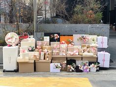 many boxes are stacked on top of each other in front of a fence with flowers