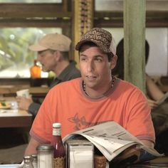 a man in an orange shirt and hat sitting at a table