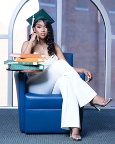 a woman sitting in a chair with books on her lap and wearing a graduation cap