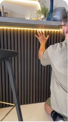 a man sitting on the floor in front of a counter with his hand up to him