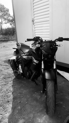 black and white photograph of two motorcycles parked in front of a building with shutters