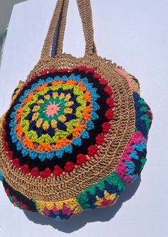 a multicolored crocheted bag sitting on top of a white tablecloth