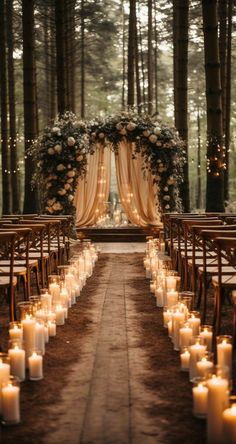 an outdoor ceremony with candles and flowers on the aisle, surrounded by tall pine trees