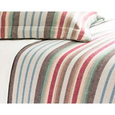 a bed with striped sheets and pillows on top of it