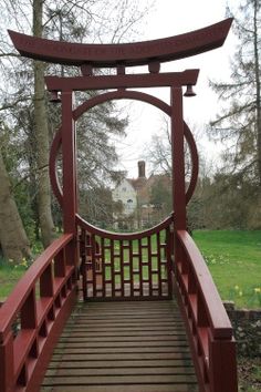 a red wooden bridge over a lush green park