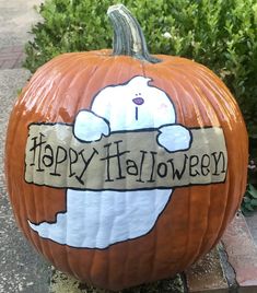 a carved pumpkin with a bunny holding a sign that says happy halloween in front of some bushes