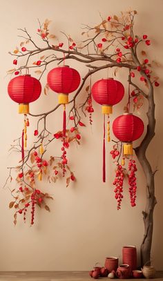 a tree with red lanterns hanging from it's branches next to cups and vases