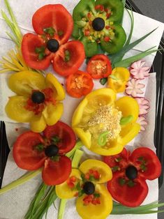 several different types of peppers on a black tray with white napkins and green leaves