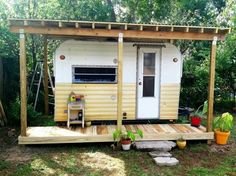 a tiny house built into the side of a wooded area with a porch and grill