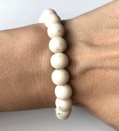 a woman's arm wearing a white beaded bracelet