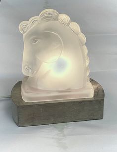 a glass elephant head on a wooden base with a light in it's mouth