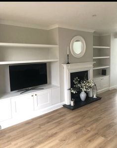 a living room with white furniture and a flat screen tv mounted on a wall above a fireplace