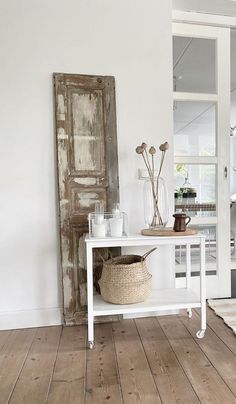 a white table sitting on top of a hard wood floor next to a wall mounted mirror