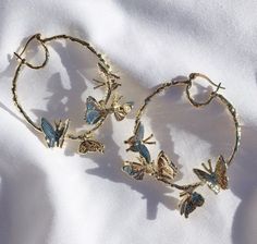 two bracelets with butterflies on them sitting on a white surface next to a woman's face