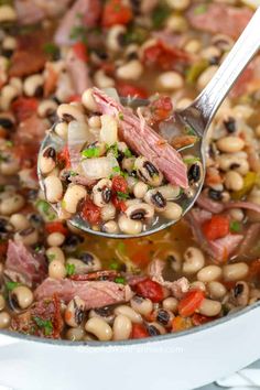 a spoon full of black - eyed beans and ham in a white pot with other ingredients