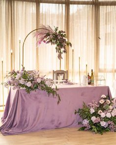 the table is covered with purple flowers and greenery