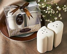 two white candles sitting on top of a plate next to a box with brown ribbon