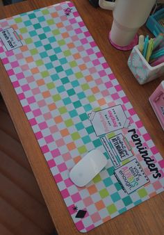 a mouse pad sitting on top of a wooden table next to a cup and other office supplies