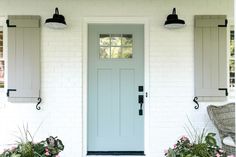 a blue front door with two planters on either side and one light hanging over it