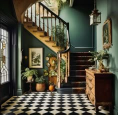 an entryway with green walls and black and white checkered flooring, potted plants on either side of the stairs