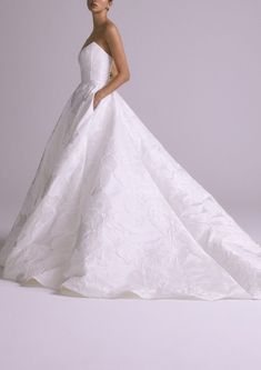 a woman in a white wedding dress posing for the camera with her hands on her hips