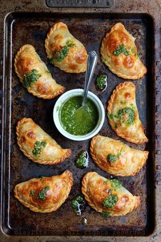 several pastries on a baking sheet with green sauce