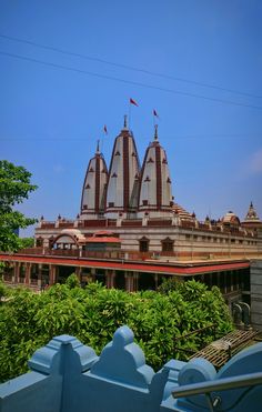 a large building with many spires and flags on it's roof, surrounded by greenery