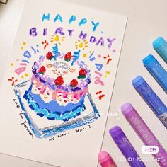 a birthday cake with candles and crayons next to it