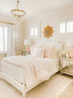 a bedroom with white bedding and pink accessories on the nightstands in front of it