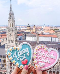 two decorated heart shaped cookies in front of a cityscape