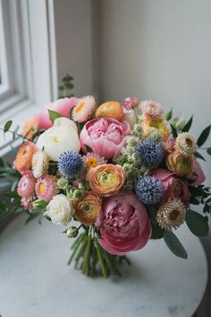 a bouquet of flowers sitting on top of a table next to a window sill