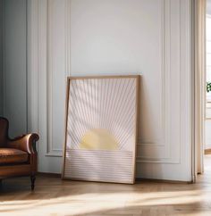 a chair sitting in front of a white wall next to a wooden framed art piece