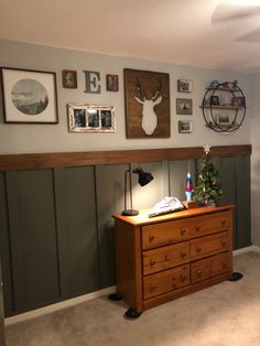 there is a dresser in the room with pictures on the wall above it and a christmas tree