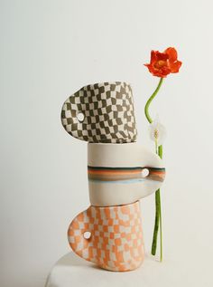 a flower that is sitting on top of a stack of stacked hats and vases