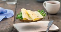 a sandwich with cheese, lettuce and other toppings sitting on a cutting board