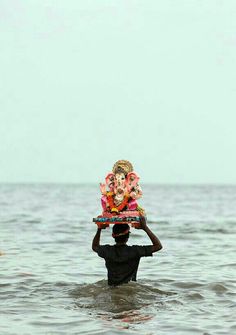 a man carrying a tray with an idol on his head in the ocean