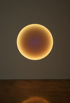 a round object is shown in the sky above a wooden table with a light shining on it