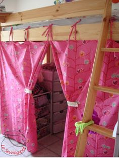 a bunk bed with pink curtains on it