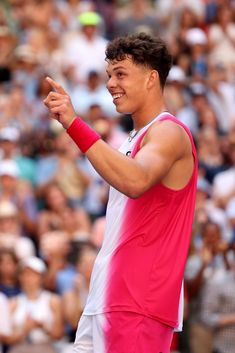 a male tennis player is holding his hand out and pointing to the side with people in the background