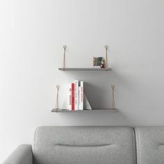 two bookshelves on the wall above a couch with a gray sofa and white walls