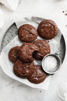 chocolate cookies with sea salt on a plate next to a glass of milk and spoon