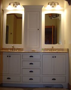 a bathroom with double sinks and two large mirrors on the wall above it is illuminated by three lights