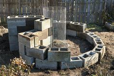 a circular concrete planter in the middle of a yard with plants growing out of it