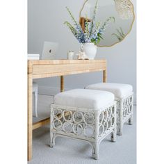 two white stools sitting under a mirror next to a table with flowers on it