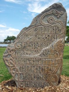 a large stone with writing on it in the grass