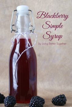 blackberry simple syrup recipe in a glass bottle with blackberries around it on a brown background