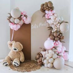 a teddy bear sitting next to a balloon arch