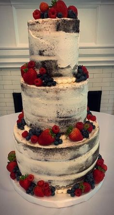 a three tiered cake with fresh berries on top