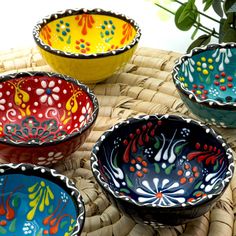 four colorful bowls sitting on top of a wicker basket